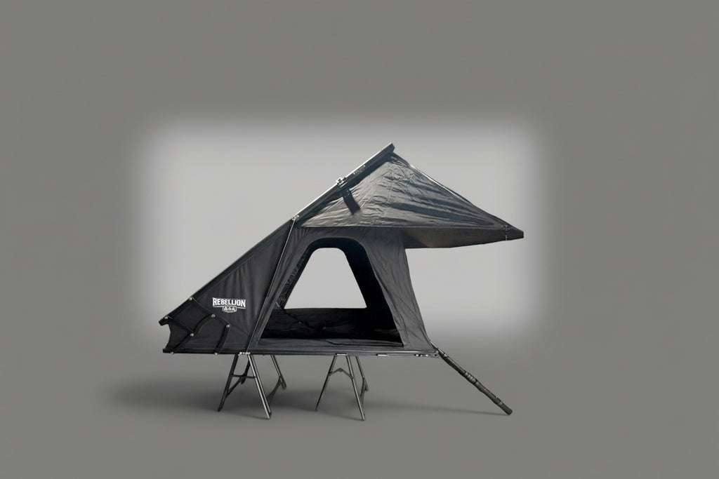 A rooftop tent shown on a gray gradient background.The tent is dark gray/black with a triangular roof shape and visible support legs.