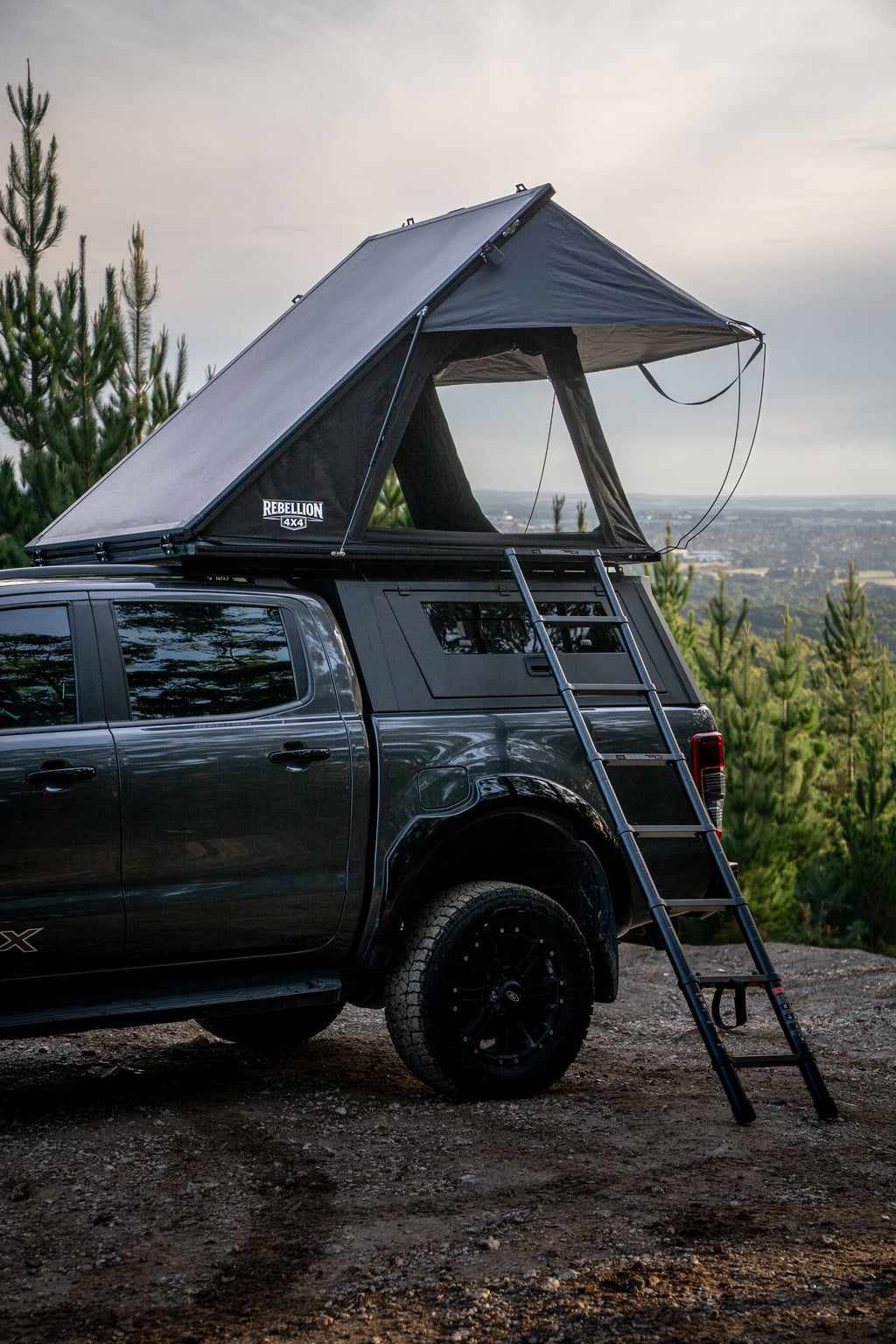 Black SUV with a rooftop tent and ladder in a forest setting