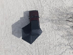 A dark gray pop-up canopy tent is pitched on a white snow-covered ground next to a dark red off-road vehicle, viewed from a high-angle aerial perspective.