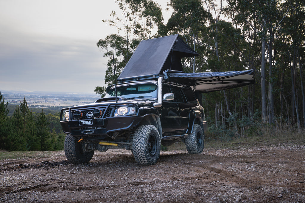 Black off-road vehicle with extended roof rack in a forested area