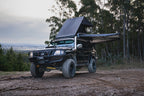 Black off-road vehicle with extended roof rack in a forested area
